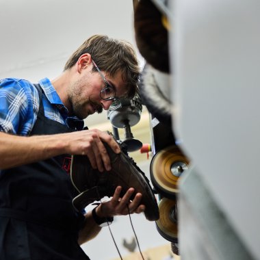 Mann trägt eine Schutzbrille und arbeitet mit einer Maschine in einer Werkstatt. | © Kleinwalsertal Tourismus eGen • Fotograf: Oliver Farys