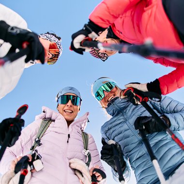 Vier Freunde mit Schneeschuhen und Skibrillen blicken nach unten, lachen und genießen eine Winterwanderung im Kleinwalsertal. | © Kleinwalsertal Tourismus eGen • Fotograf: Oliver Farys